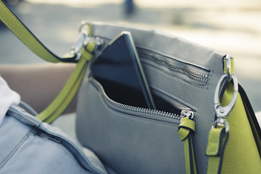 Women's handbag with the phone on the street close up