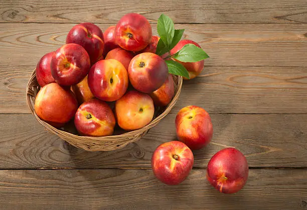 Nectarines in basket on a wooden table