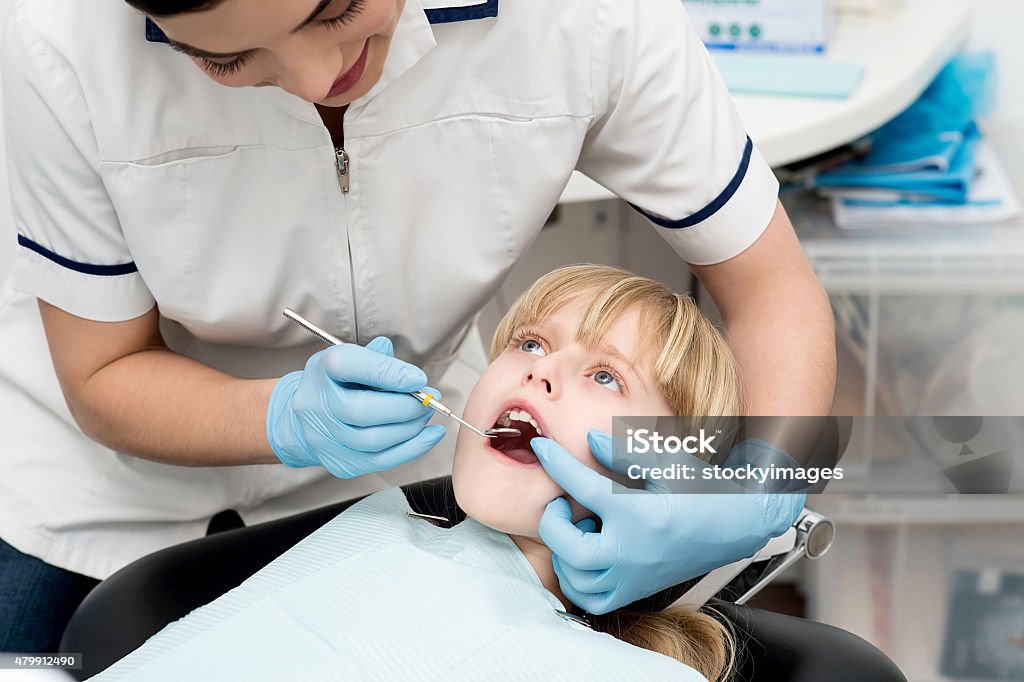 Little girl on dental check up. Cute kid undergoing dental treatment at clinic 2015 Stock Photo