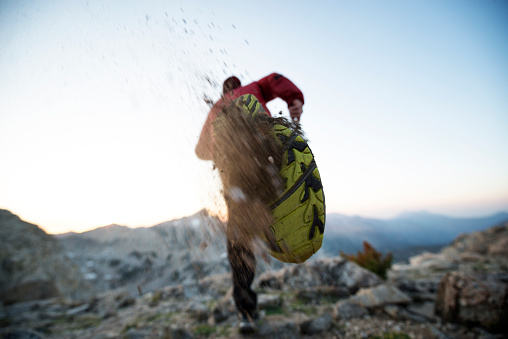 Fit endurance athlete running in the mountains kicking up dirt from his shoe 