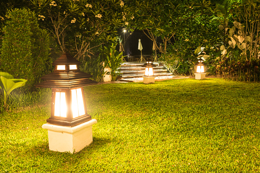 Garden lamp shine orange light in garden of hotel resort at night