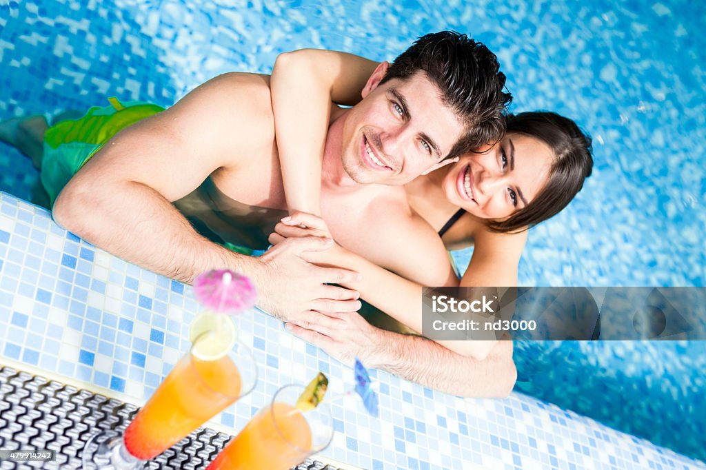 Couple drinking a cocktail by the swimming pool and relaxing 2015 Stock Photo