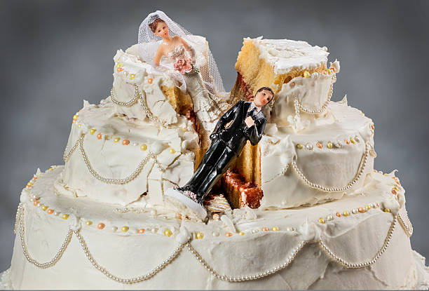 Bride and groom figurines collapsed at ruined wedding cake stock photo