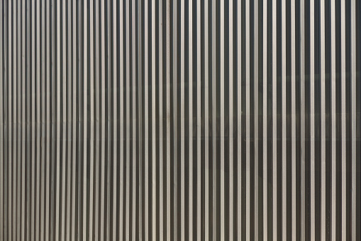 Linear geometric background or texture silvery gray color. Metal structure covered car park facade - Fondo o textura geometrico lineal de color gris plateado . Estructura metalica de chapa perforada