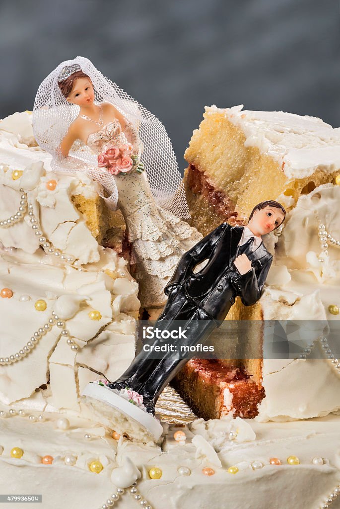 Bride and groom figurines collapsed at ruined wedding cake Spouses always seem to struggle to keep their relationship alive Wedding Cake Figurine Stock Photo