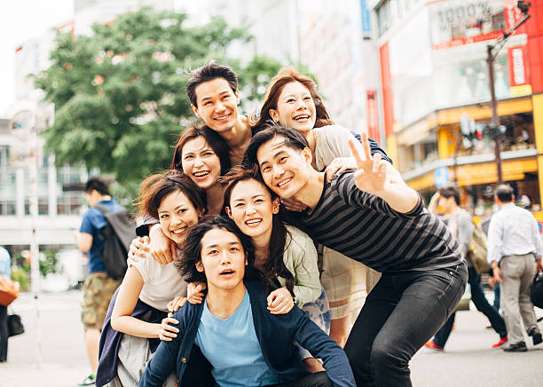 Young people  having fun against cityscape.  All people in the image are  worn with casual clothes. Background is blurred  buildings around Shibuya crossing in Tokyo. Concept for urban lifestyle and friendship. Image is taken during Tokyo Istockalypse 2015