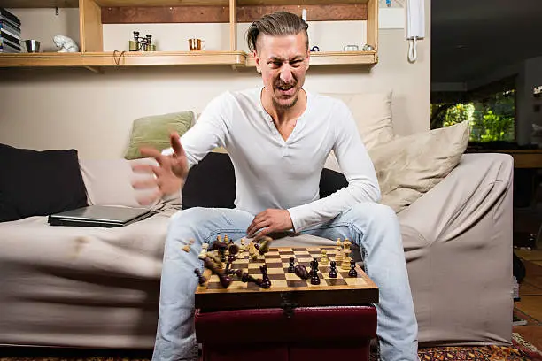 An image of a Caucasian guy sitting on a couche playing chess