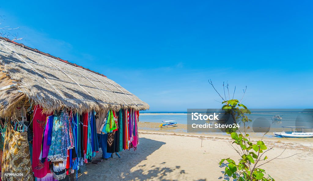 Beach Market in Bali Market on the beach in Bali with boats in the background resting on the sand at low tide and a perfect blue sky overhead . Bali Stock Photo