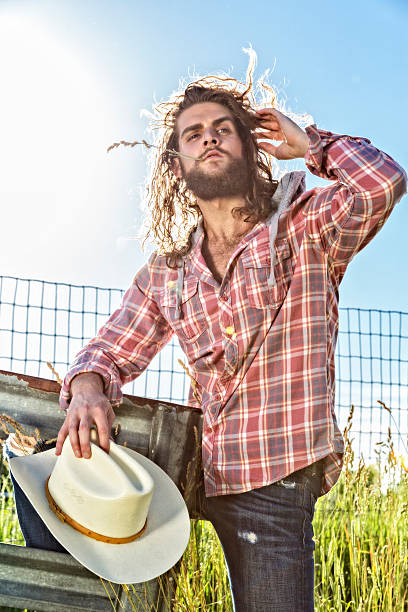 istock Young Man Looks Out Over Field While Holding Cowboy Hat 479954310