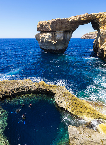 The famous limestone natural arch known as Azure Window with scuba drivers in deep pool near Dwejra Bay on island Gozo on Malta. It is popular tourist place as scuba divers to.