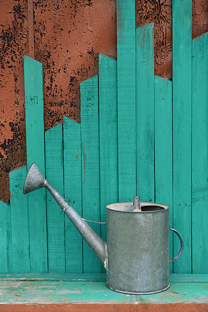 istock Old watering can on green wooden background 479960166