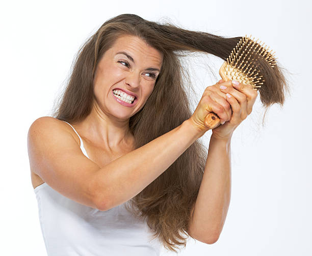 femme en colère ayant mal à se peigner les cheveux - hair care combing women human hair photos et images de collection