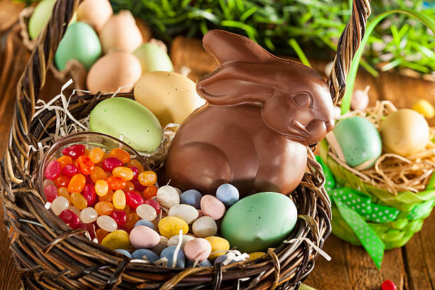 Chocolate Easter Bunny in a Basket Chocolate Easter Bunny in a Basket with Assorted Candy chocolate bunny stock pictures, royalty-free photos & images