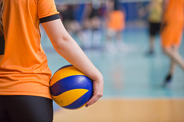Volleyball Training Woman volleyball player is watching the game with holding a volley ball on her hand. young volleyball girl stock pictures, royalty-free photos & images