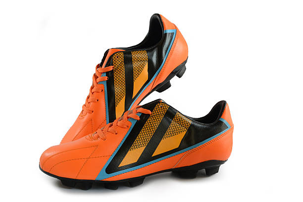 botas naranjas de fútbol americano sobre fondo blanco - botas de fútbol fotografías e imágenes de stock