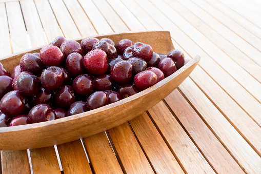 Bowl of sweet cherries on wooden table