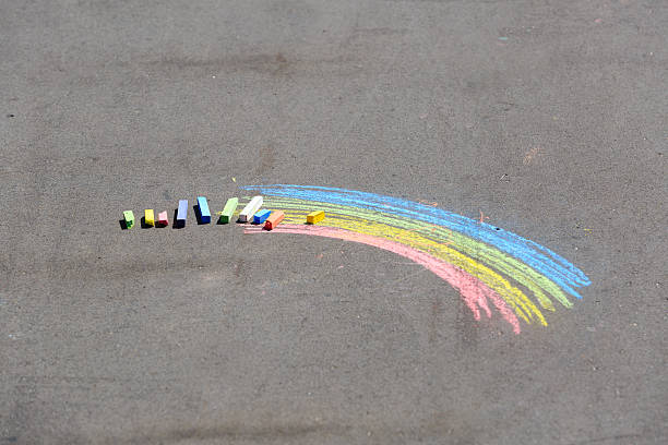 istock child's drawing of rainbow and chalks on a street 479993284