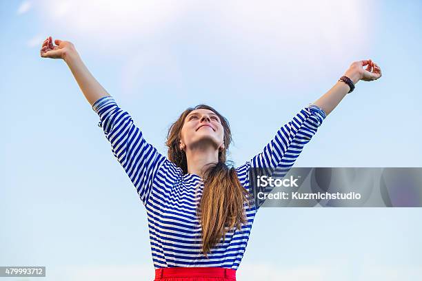 Foto de Mulher Mantém As Mãos Para A Luz Do Sol Contra O Céu e mais fotos de stock de Roupa de Marinheiro