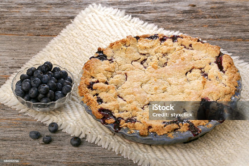 Whole Blueberry Pie Blueberry pie and berries on rustic wooden table with place mat 2015 Stock Photo