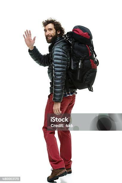 Smiling Male Hiker Waving Hand And Walking Stock Photo - Download Image Now - Cut Out, Hiking, White Background