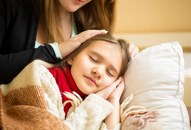 istock mother holding hand on sleeping daughters head 480004538