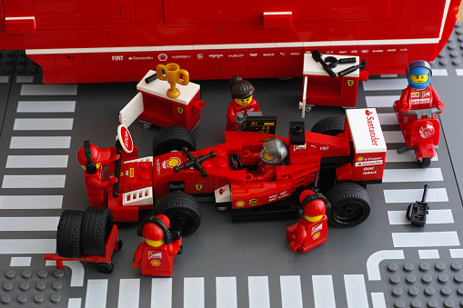 Tambov, Russian Federation - June 23, 2015: Lego team crew members are fixing wheel of Ferrari F14 T race car by LEGO Speed Champions. Studio shot.