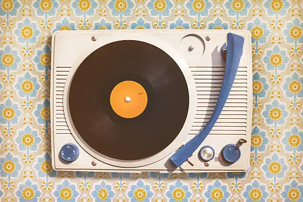 Retro styled image of an old record player on top of flower wallpaper