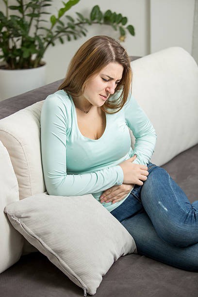 istock woman with abdominal ache sitting on sofa 480012850