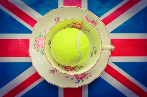 A tennis ball inside of a cup and saucer on a union jack flag