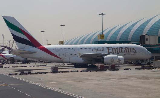 Al Garhoud district, Dubai: Emirates Airbus A380-842 (A6-EUM) at a passenger boarding bridge, seen from the terminal, with curved window frames - Dubai International Airport, terminal 3.