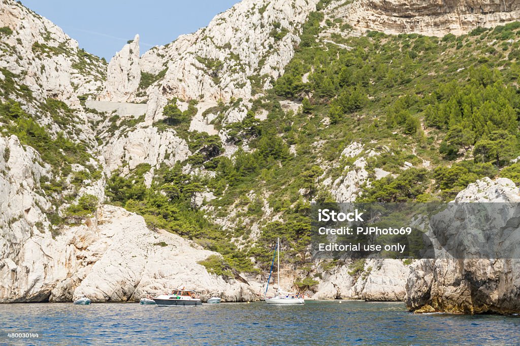 Cruising in Calanques area of Cassis Cassis, France - August 22, 2014: Cruising in Calanques area of Cassis. Many touristic boats on little bay of a Calanque. Many people sunbathing on the rocks near the beach. 2015 Stock Photo