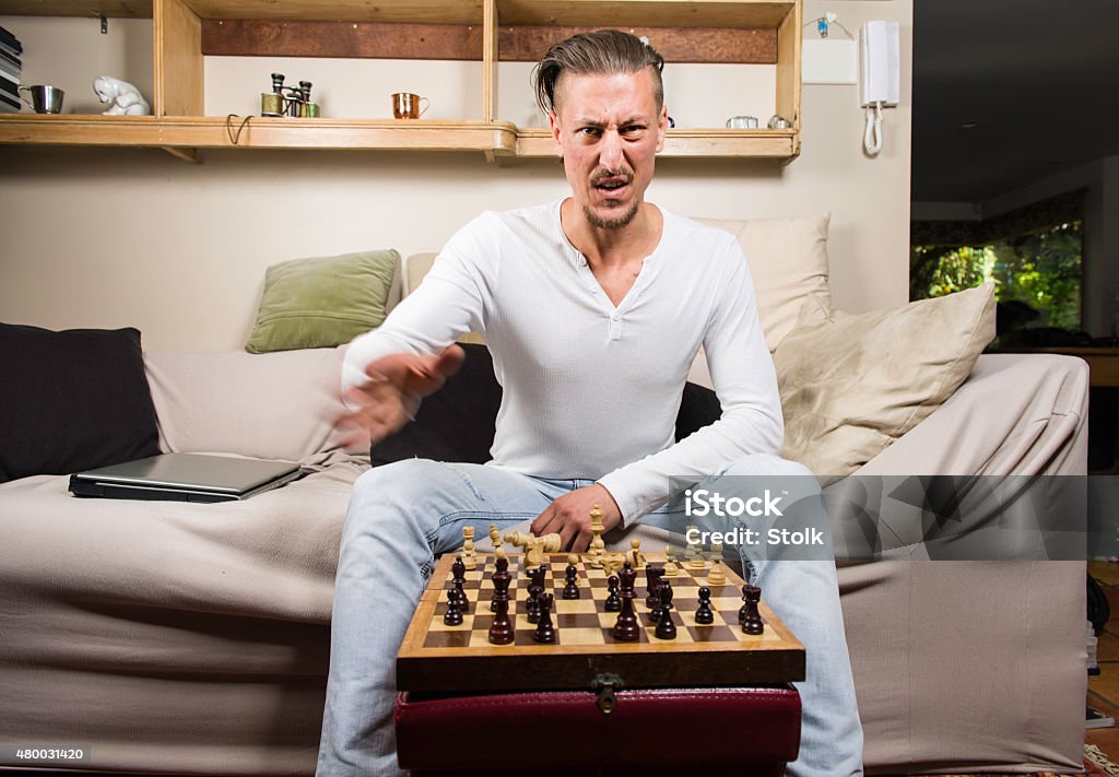 Bad move An image of a Caucasian guy sitting on a couche playing chess Anger Stock Photo