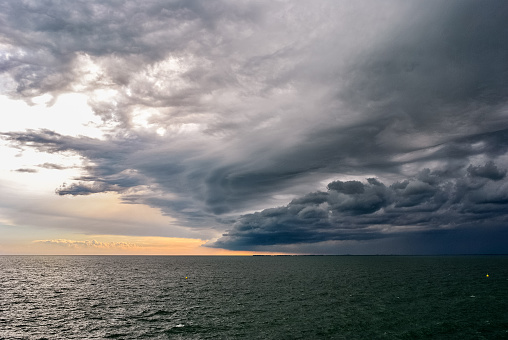 An approaching storm creates a turbulent sky above the sea, near the harbor of Trieste