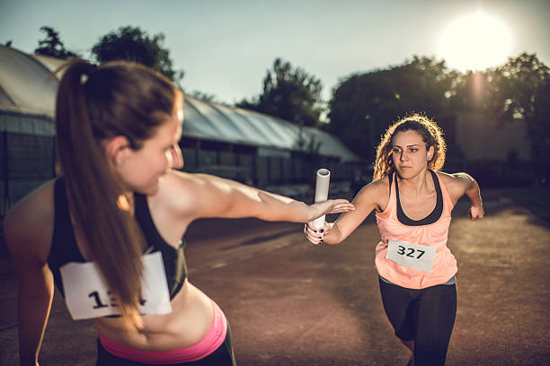 istock Women exchanging relay baton on a sports race. 480048076