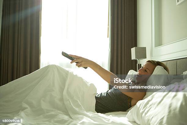 Cheerful Girl Watching Tv From Bed Stock Photo - Download Image Now - Bedroom, Television Set, 2015