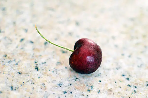 Ripe red sweet cherry with stem on marble counter