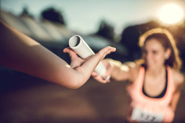 close-up da troca de bastão de corrida em uma corrida desportiva. - unrecognizable person sky athlete competitive sport - fotografias e filmes do acervo