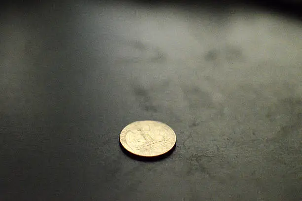 Quarter coin on somber cherry wood desk