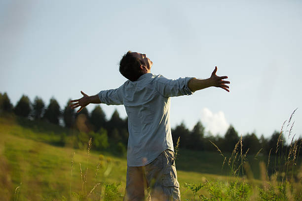 istock Guy with outstreched arms standing in a meadow 480057568