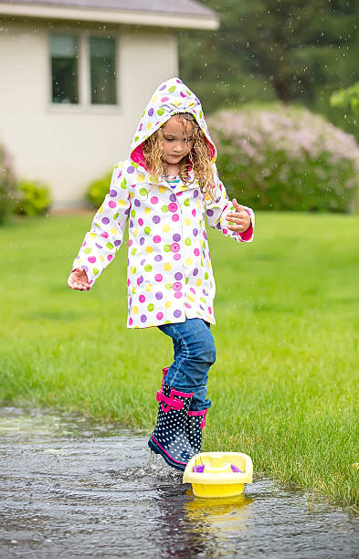 istock Young Girl Playing With Toy Boat in Rain Puddle 480061118