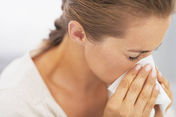 istock woman blowing nose into handkerchief 480071761
