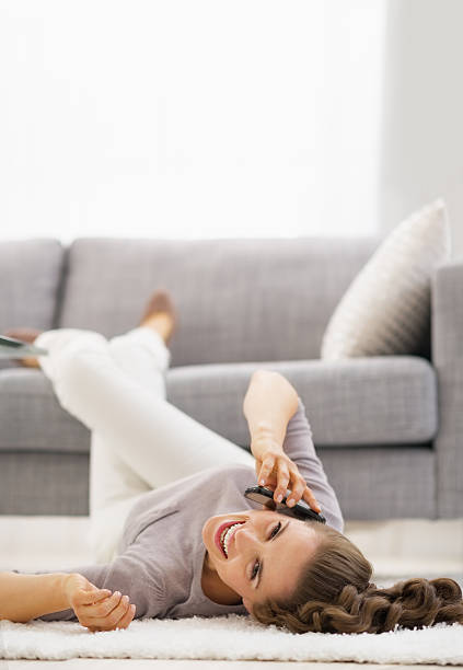 istock smiling young woman talking mobile phone while laying on floor 480071985