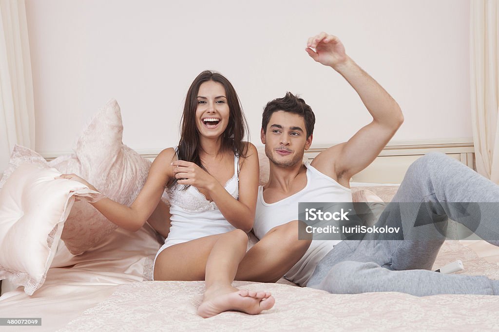 Happy couple in bedroom Young couple fighting pillows in the bedroom Activity Stock Photo