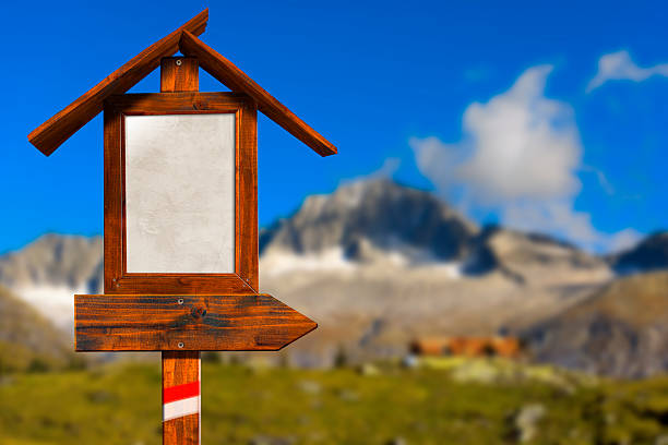 Empty wooden directional sign with roof in a blurred mountain landscape