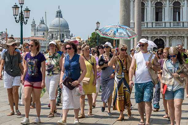 Tourists follow their tour guide through St Mark's Square, Venice stock photo