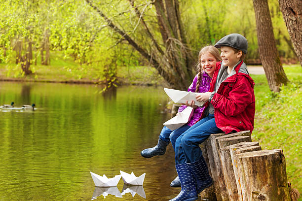 rir menina e menino perto de lago com barcos de papel - ticket ticket stub park fun imagens e fotografias de stock