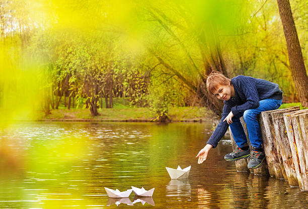 istock Boy holding arm to play with white paper boats 480080954