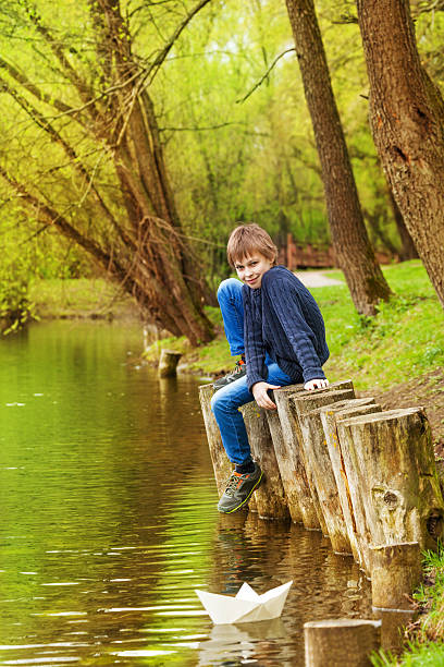 rapaz sentado com bended joelho perto do lago - ticket ticket stub park fun imagens e fotografias de stock