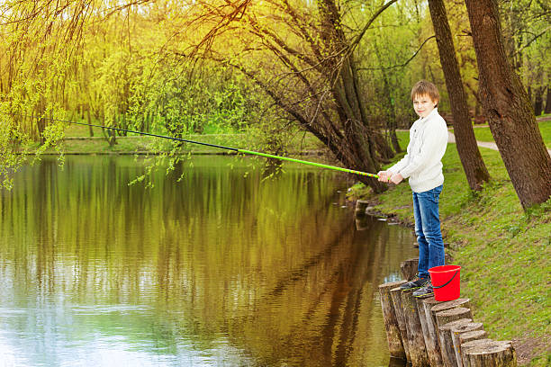 menino de pé perto do lago e pesca - ticket ticket stub park fun imagens e fotografias de stock