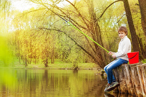 rapaz pesca perto do lago com verde fishrod - ticket ticket stub park fun imagens e fotografias de stock